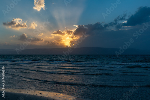 Foto Cloudy Sunset of Blue and Gold with Golden Rays Over the Sea of Galilee, Israel,