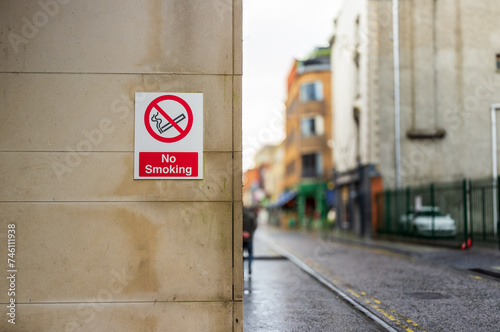 No smoking sign on a wall. Out of focus street in background