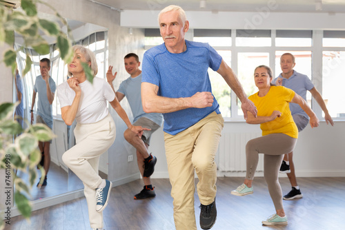 Portrait of active mature people enjoying modern energetic dancing in a group in the studio