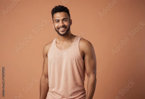 A man in a peach tank top shows a relaxed and happy demeanor, set against a peach background.