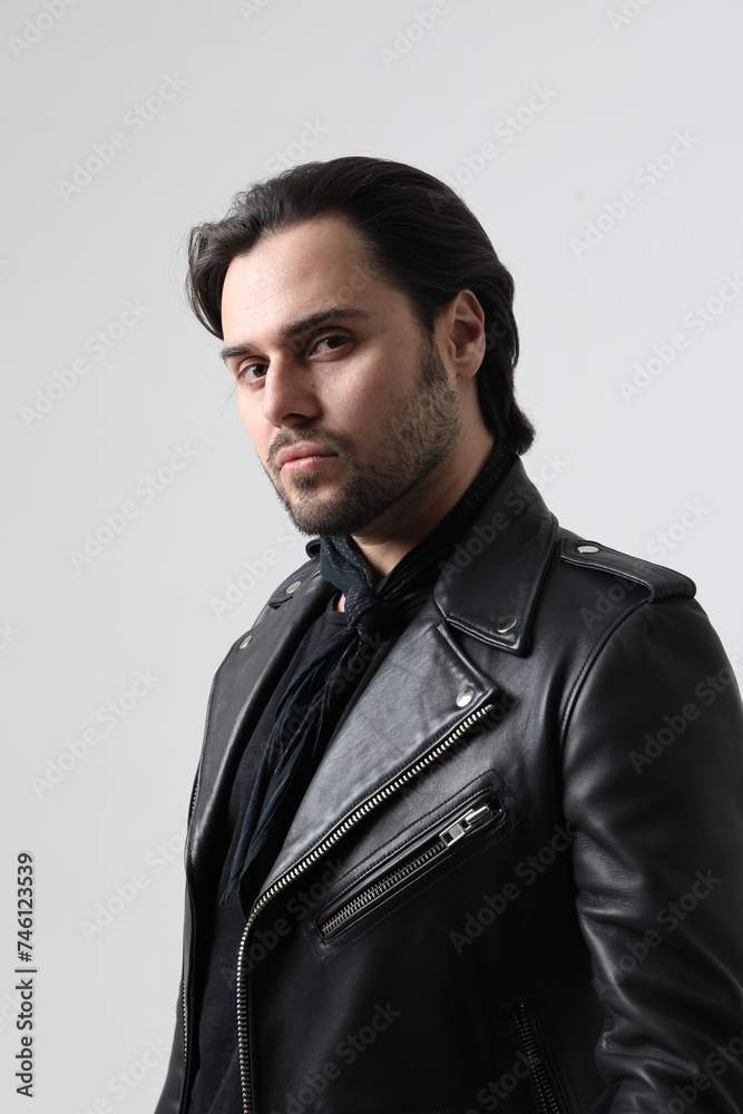 Stylish bearded young man wearing biker jacket looking at the camera. Vertical. Stylish bearded young man wearing biker jacket looking at the camera. Vertical.