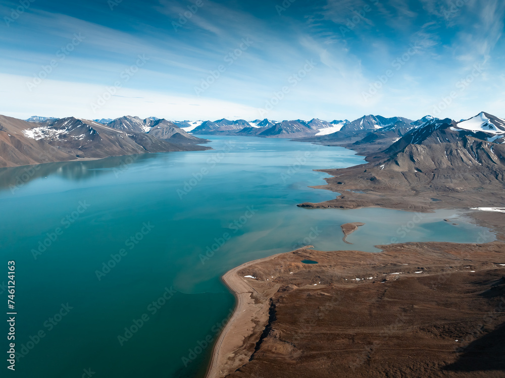 drone shot for breathtaking footage of wild nature in svalbard, majestic mountains in the clouds, massive river and nature under the cloud, useful for newspapers and magazines, travel to unspoiled 