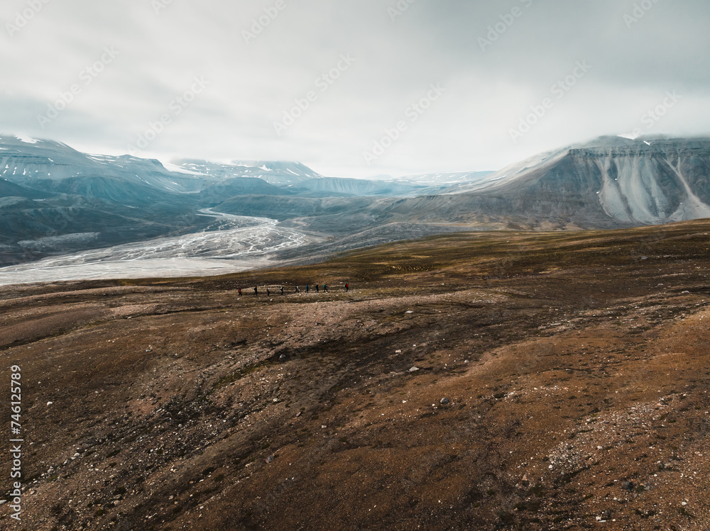 a shot from a drone of breathtaking footage of wild nature in Svalbard, majestic mountains in the clouds, a mighty river and nature under the cloud, a frozen glacier in the middle of the mountains, 