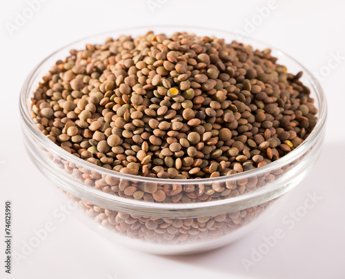Lentils in a glass cup on a white surface