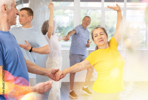 Elderly men and wome learn energetic twist dance in choreography studio photo