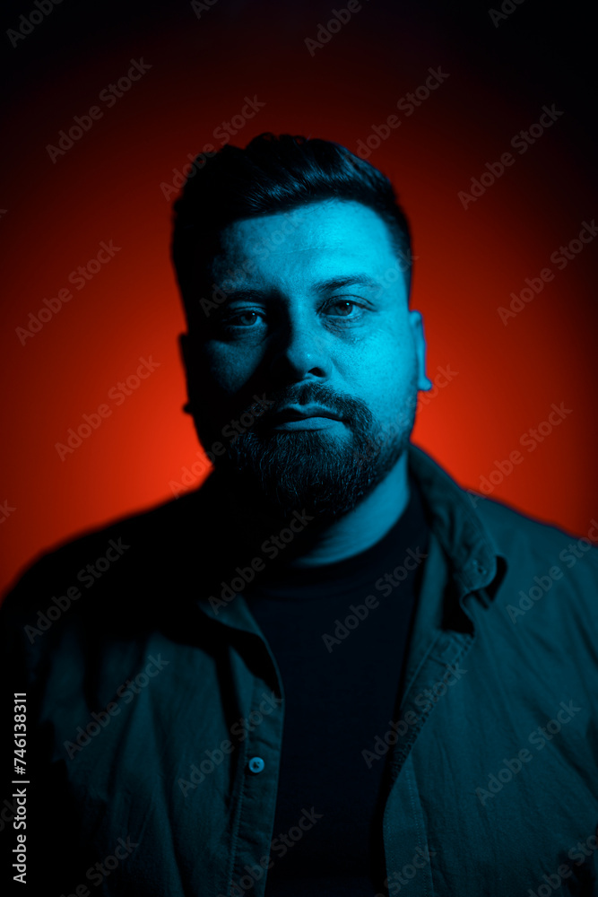 Dramatic portrait of a bearded man, his face split by contrasting blue and red lighting