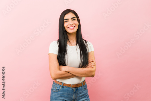 Attractive woman looking happy and smiling in a pink background