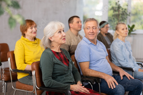 Tablou pe pânză Focused motivated older woman listening to lecture in auditorium with group