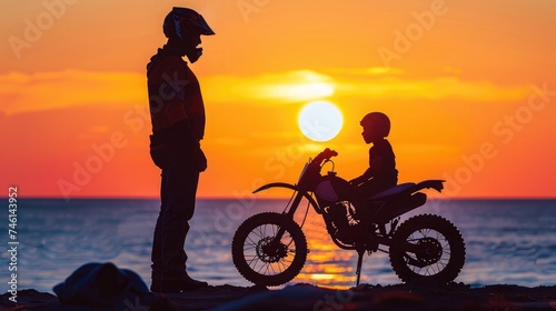 Biker family silhouette   daddy and son at the beach at sunset.