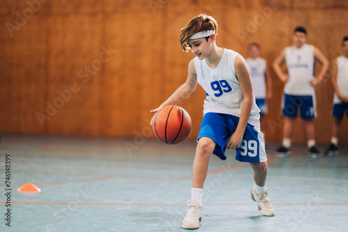 A junior basketball player is dribbling a ball and learning moves. photo