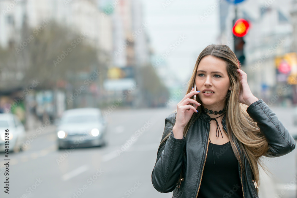 Portrait of attractive woman talking on mobile phone. Dreamy hipster girl enjoying leisure time while walking at spring urban setting with gadget Portrait of attractive woman talking on mobile phone. Dreamy hipster girl enjoying leisure time while walking at spring urban setting with gadget