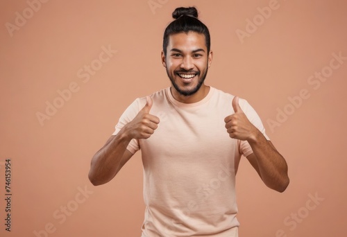 An enthusiastic man in a peach shirt gives double thumbs up. The warm peach background highlights his energetic spirit.