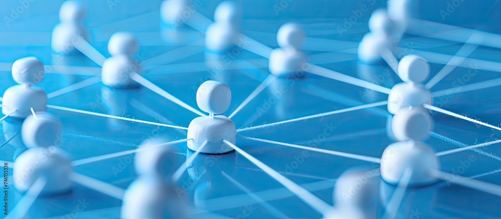 A group of small white figurines are positioned on a blue surface, symbolizing connected networking. The scene represents communication and marketing strategies in a simplistic visual form. - obrazy, fototapety, plakaty 