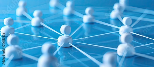 A group of small white figurines are positioned on a blue surface, symbolizing connected networking. The scene represents communication and marketing strategies in a simplistic visual form. photo
