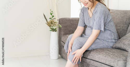 家のソファに座る妊婦・マタニティ（ふくらはぎ・マッサージ・こむら返り・妊娠後期）
 photo