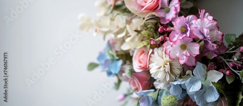 A detailed view of an artificial flower funeral wreath with vibrant colors, displayed on a white wall.