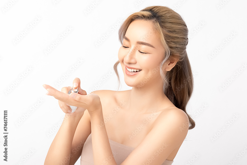 Happy Asian woman applying perfume on her wrist, enjoying the fragrance with a delightful smile on white background. Facial treatment, Perfect skin, Natural make up. Happy Asian woman applying perfume on her wrist, enjoying the fragrance with a delightful smile on white background. Facial treatment, Perfect skin, Natural make up.