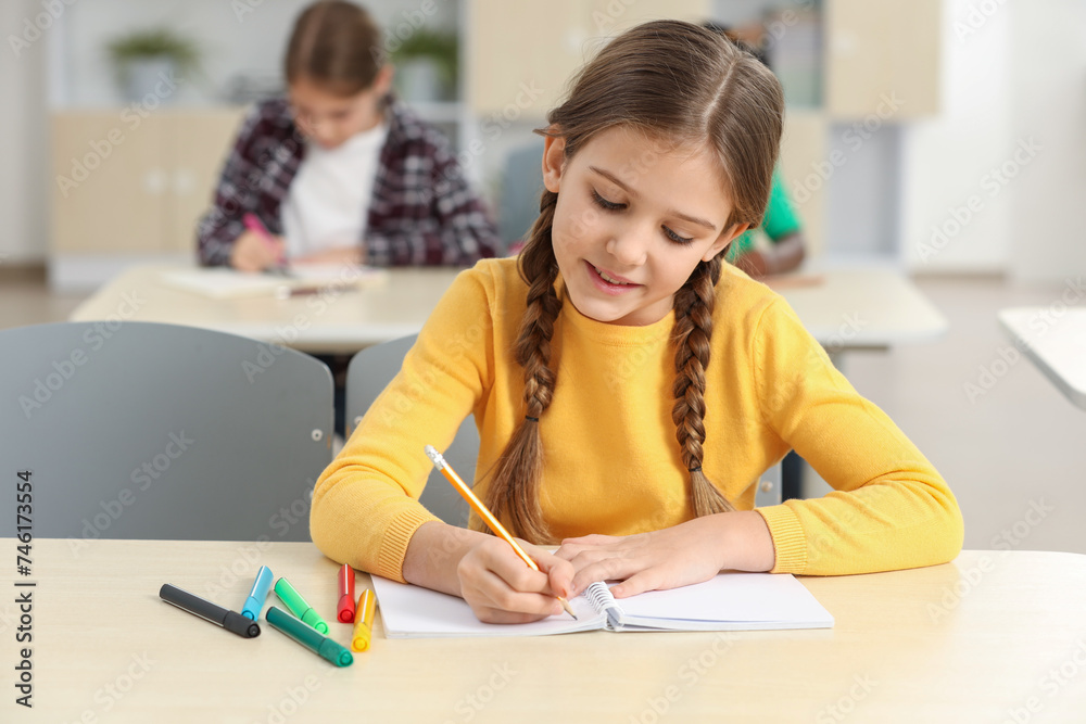 Smiling little girl studying in classroom at school Smiling little girl studying in classroom at school