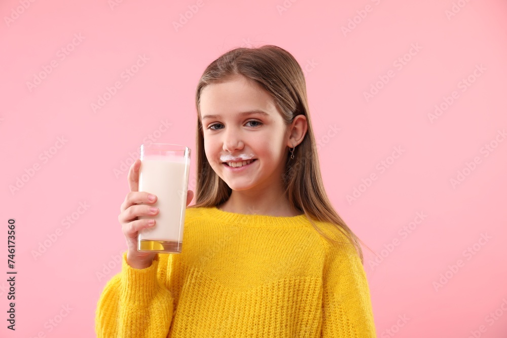 Happy little girl with milk mustache holding glass of tasty dairy drink on pink background Happy little girl with milk mustache holding glass of tasty dairy drink on pink background