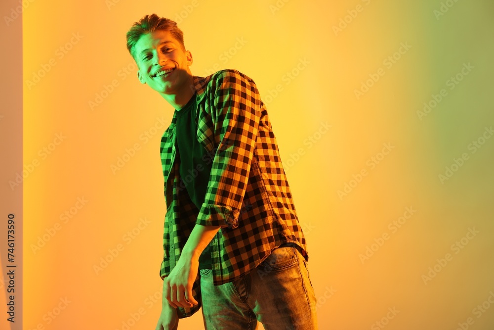 Young man dancing on color background in neon lights