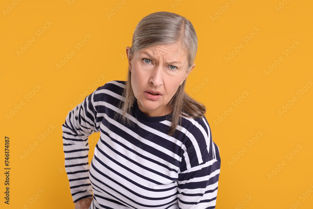 Portrait of surprised senior woman on yellow background Portrait of surprised senior woman on yellow background