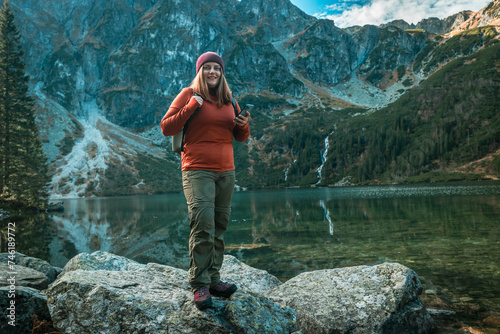 Shot of woman traveler relaxing alone travel in adventure vacation with backpack enjoying standing on the top of the mountain near Famous mountains lake Morskie oko or sea eye lake In High Tatras. 