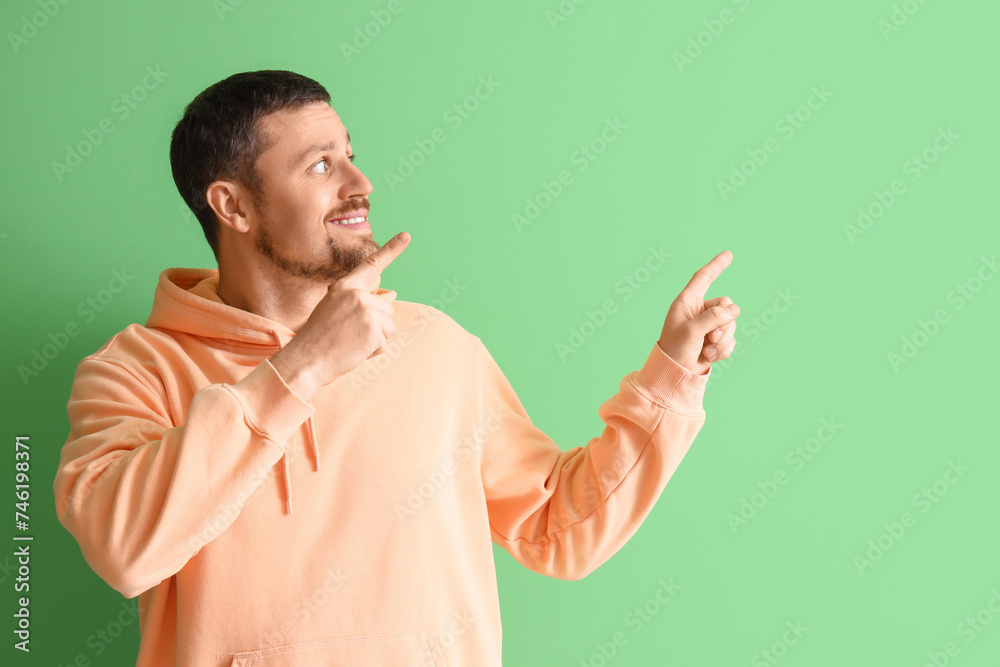 Handsome man pointing at something on green background Handsome man pointing at something on green background