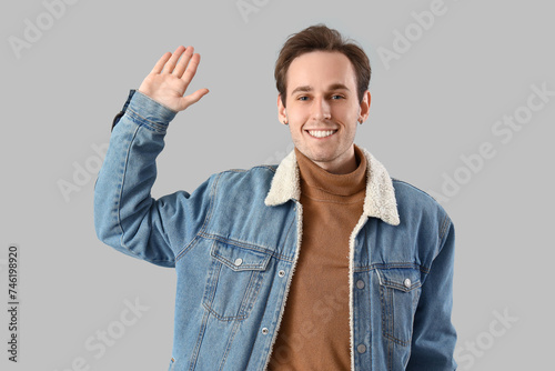 Young man waving hand on li...