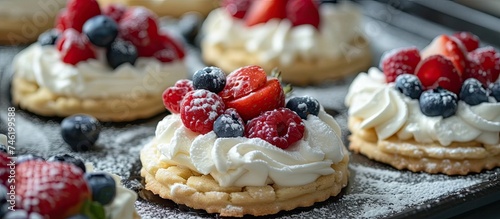 A close up view of a tray filled with cookies that have been filled with fresh fruits and topped with whipped cream.