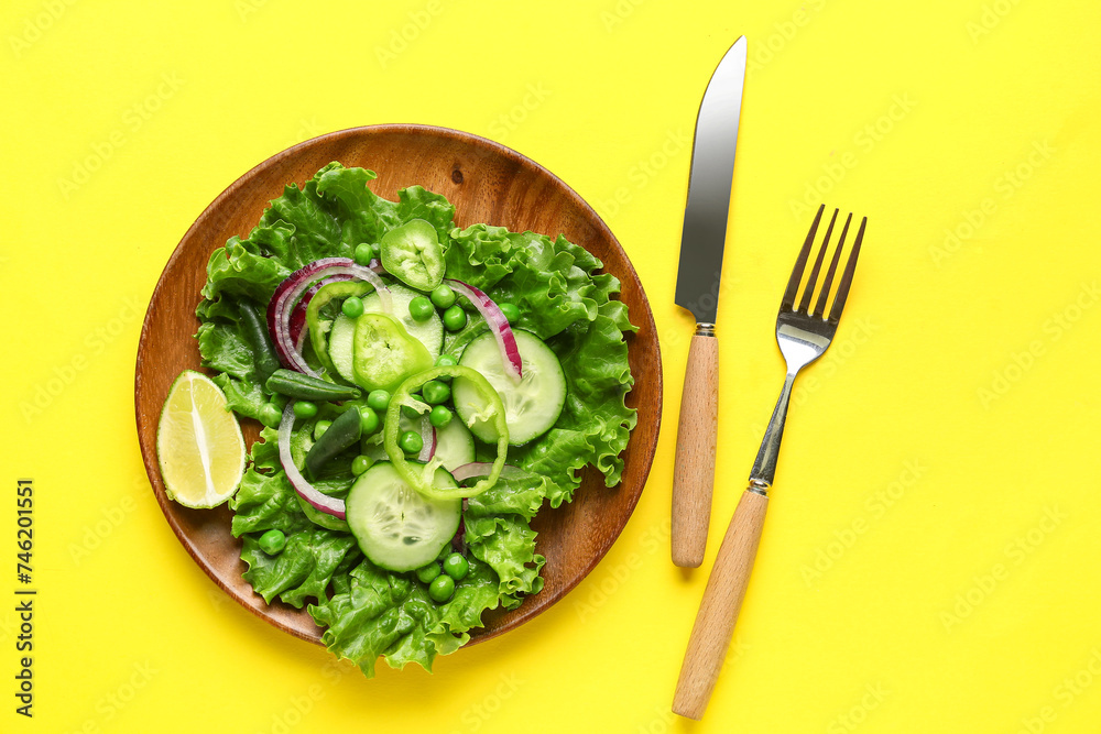 Plate of tasty vegetable salad on yellow background Plate of tasty vegetable salad on yellow background