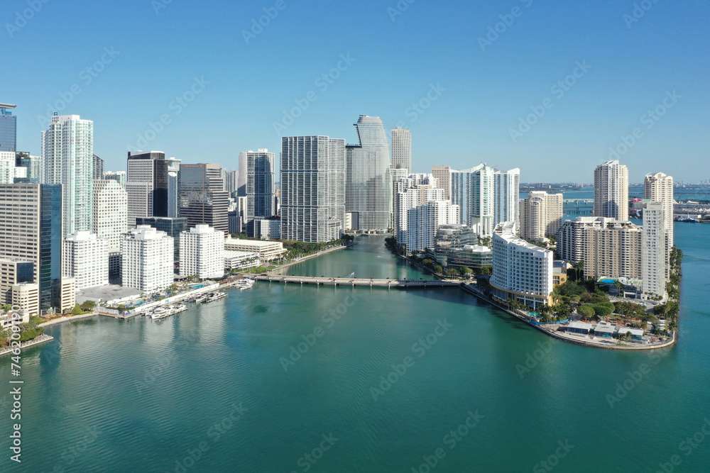 Aerial image of waterfront residential buildings in Brickell neighborhood of Miami, Florida reflected in calm water of Biscayne Bay on sunny morning.