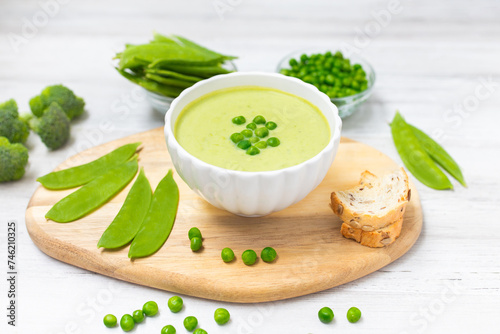 Cream soup with green peas on white wooden table. Healthy, diet food. Vegetarian food. 