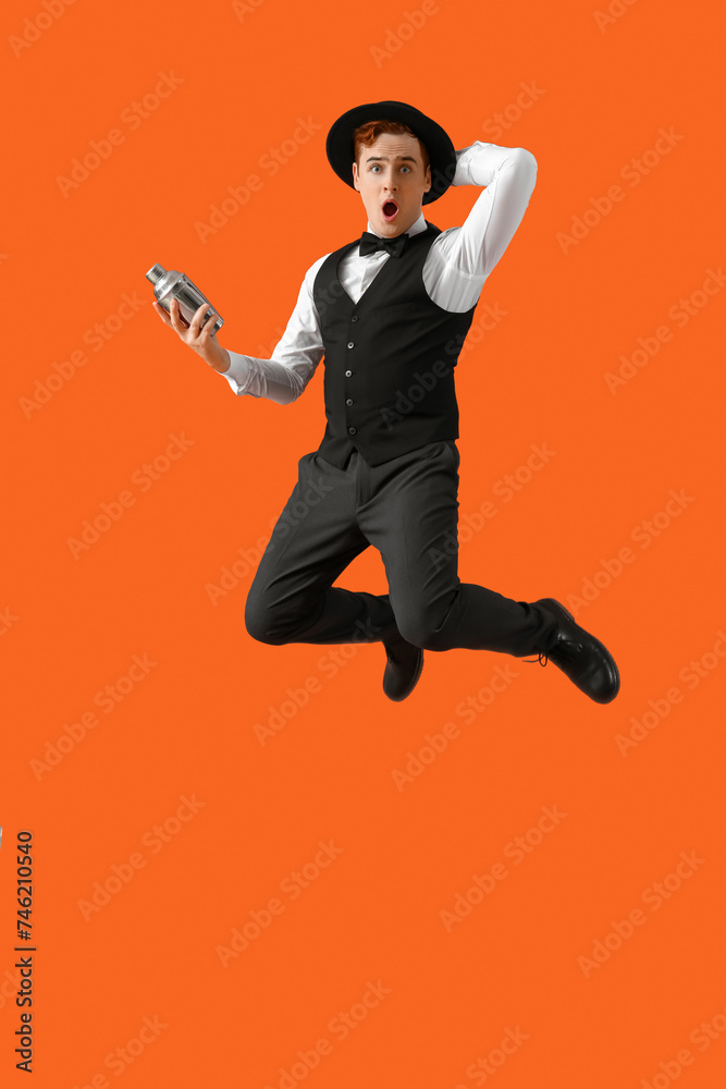 Jumping male bartender with shaker on orange background