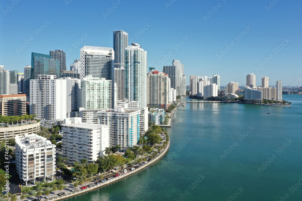 Obraz premium Aerial image of waterfront residential buildings in Brickell neighborhood of Miami, Florida reflected in calm water of Biscayne Bay on sunny morning.