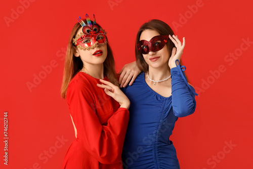Beautiful young women in carnival masks on red background