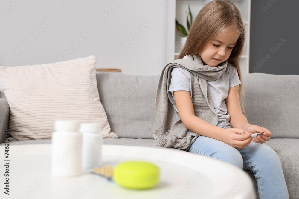Sick little girl with thermometer sitting on sofa at home Sick little girl with thermometer sitting on sofa at home
