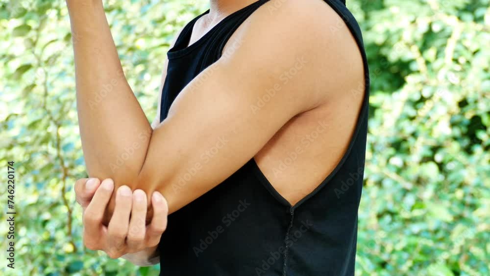 An Asian man Pain in his elbow, he holds his elbow because of the pain. An Asian man Pain in his elbow, he holds his elbow because of the pain.