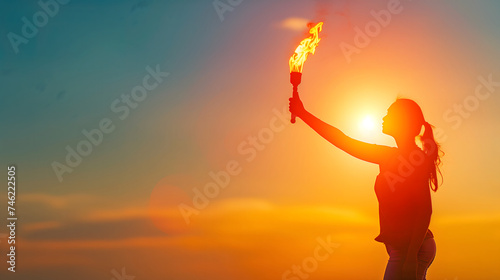 Dramatic lighting on a female figure who is holding a torch of empowerment on a dawn sky as a background for Women's Day social presentation.