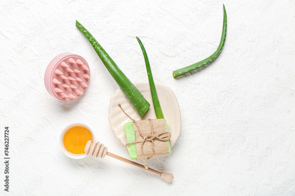 Hair scalp massager with shampoo bar, bowl of honey and aloe vera on white background Hair scalp massager with shampoo bar, bowl of honey and aloe vera on white background
