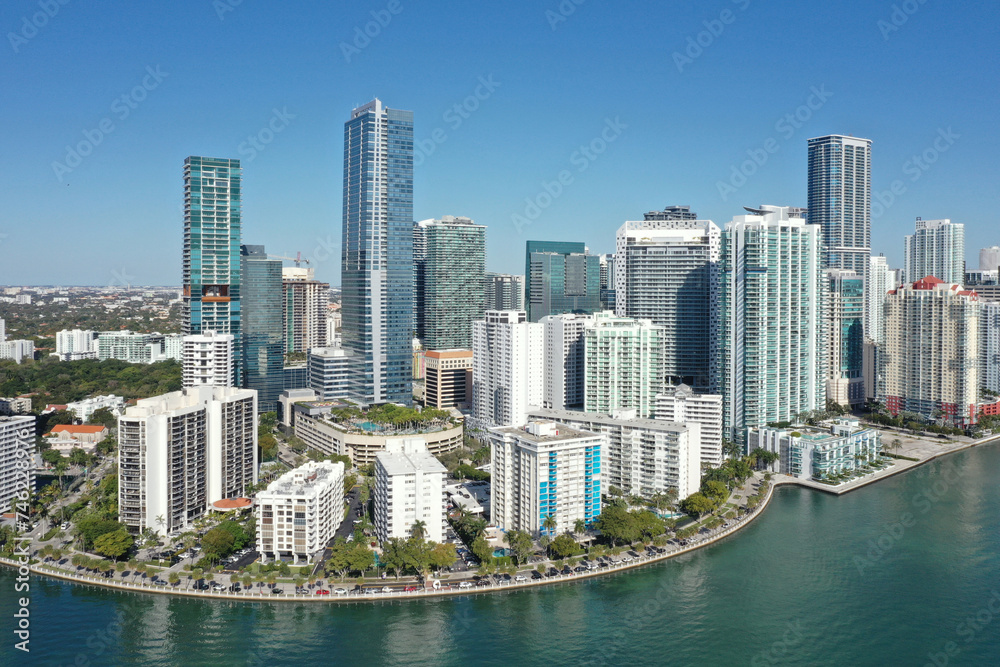Obraz premium Aerial image of waterfront residential buildings in Brickell neighborhood of Miami, Florida reflected in calm water of Biscayne Bay on sunny morning.