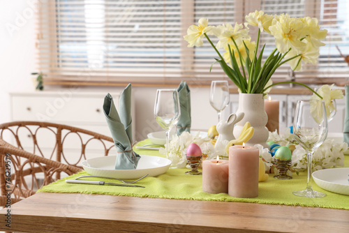 Festive table setting with vase of yellow tulips, candles and Easter bunnies © Pixel-Shot