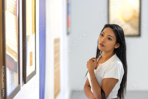 Φωτογραφία A young woman looks at paintings at an exhibition