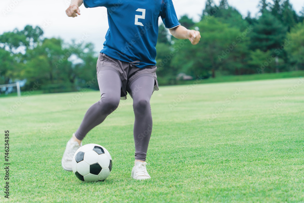 サッカーボールをドリブルする女性の足元
