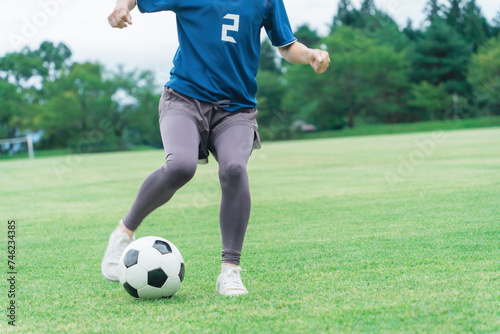 サッカーボールをドリブルする女性の足元  © buritora