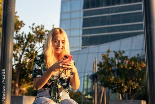 Blonde girl using mobile phone outdoors