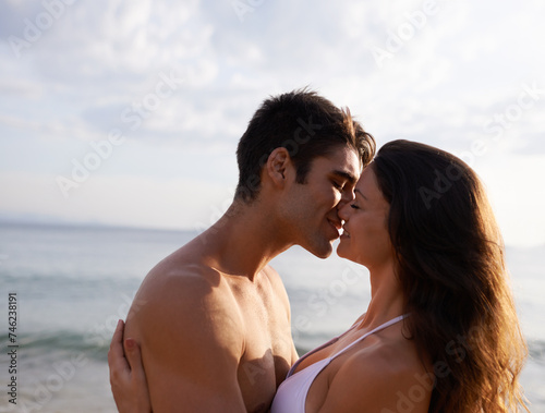 Beach, kiss and couple with love on holiday or travel on vacation together at sea in summer. Romantic, date and man show gratitude for woman and smile with kindness, care and support for partner