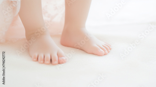 Toddler's Tiny Feet Standing on White Surface. First Steps and Childhood Development Concept © AspctStyle