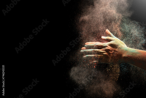 Closeup of hand holding colorful holi powder isolated over black background.