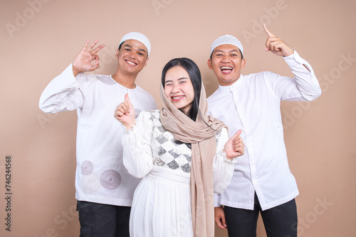 Group of young Asian friends smiling and showing variation of hand gesture over beige background