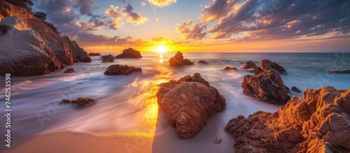 A vertical view capturing the captivating coastal rocks as the sun sets over the ocean. photo